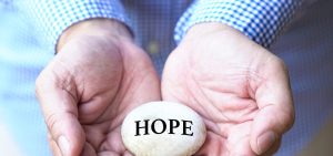 Man holding rock in palm of hands with the words hope. Hope after suicide