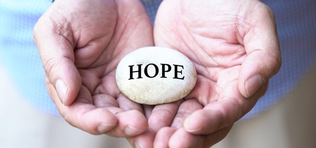Man holding a rock in palm of his hands to represent hope after a suicide.