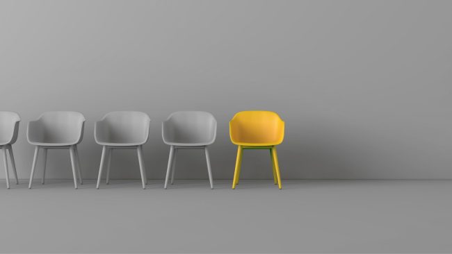 a row of grey chairs and one yellow chair